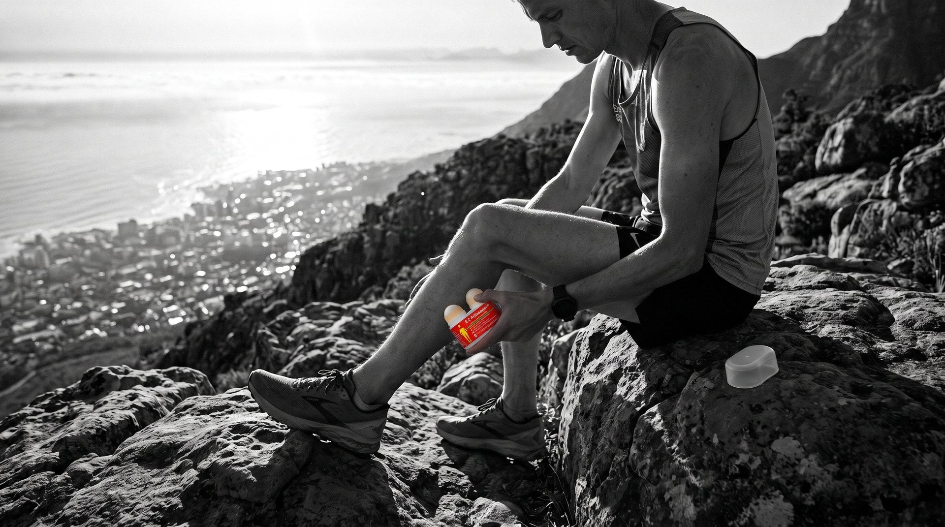 Trail runner rolling a calf on a mountain trail above Cape Town at dawn